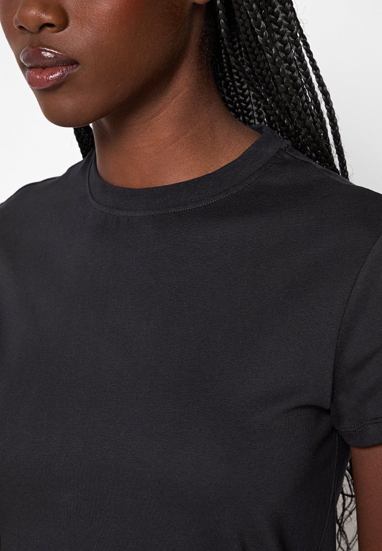 T-shirt en coton noir à manches courtes, col rond et texture lisse. Gros plan mettant en avant la qualité et l'ajustement du tissu.