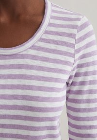 Gestreiftes langärmliges Oberteil in Helllila und Weiß. Verfügt über einen runden Ausschnitt und ein weiches, strukturiertes Baumwollmaterial.