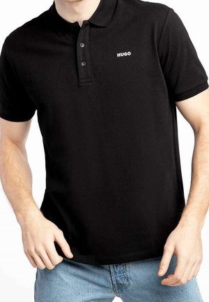 Man wearing a black short-sleeve polo shirt with a two-button placket and "HUGO" logo on the left chest, paired with light blue jeans.