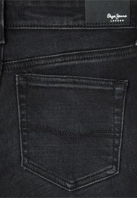 Črne denim hlače z vidnim zadnjim žepom. Imajo šivano obrobo in subtilno teksturo. Vključujejo črno etiketo z napisom "Pepe Jeans London."