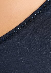 Navyblaues Oberteil mit glatter Textur und Rundhalsausschnitt, versehen mit einer Reihe kleiner schwarzer Strasssteine entlang des Randes.