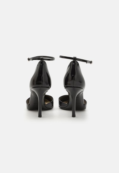 Pantofi cu toc înalt din piele lăcuită neagră, cu curea la gleznă, vârf ascuțit elegant și toc subțire stiletto. Textură simplă, fără modele vizibile.