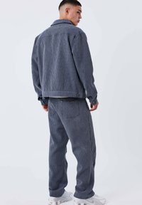 Ensemble veste et pantalon en jean à carreaux bleus avec une finition texturée. Comprend une veste à col et des détails de coutures visibles.