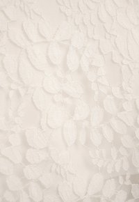 Weißes Spitzenmusterstoff mit einem Blattmuster, einer strukturierten Oberfläche und subtiler Oberflächenschönheit, die ein zartes und filigranes Design schafft.