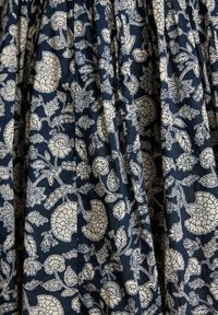 Marineblauter Stoff mit weißem Blumenmuster, das verschiedene Blumen und Blätter in einem sich wiederholenden Design mit Falten anordnet.