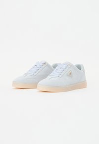 Lyseblå ruskindsneakers med lavt design, rund tå og beige gummisål. Har snørebåndslukning og en trekantet logoaccent.
