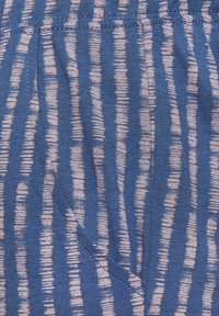 Plava tkanina s teksturiranim prugastim uzorkom u svijetlo ružičastoj boji. Ima elastičnu traku u struku i bočnu džepu. Mekani, prozračni materijal.