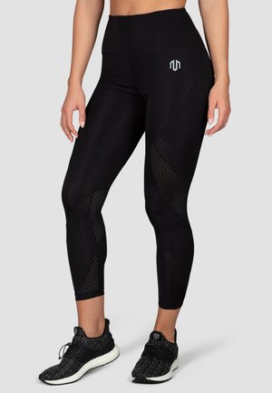Black athletic leggings with a high waistband, featuring mesh panels and a geometric pattern. Paired with black textured sneakers.