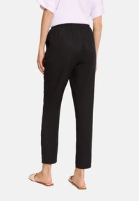 Czarne, lekkie spodnie dresowe z elastycznym pasem i zwężanym krojem. Gładka faktura o minimalistycznym designie, długość do kostek.