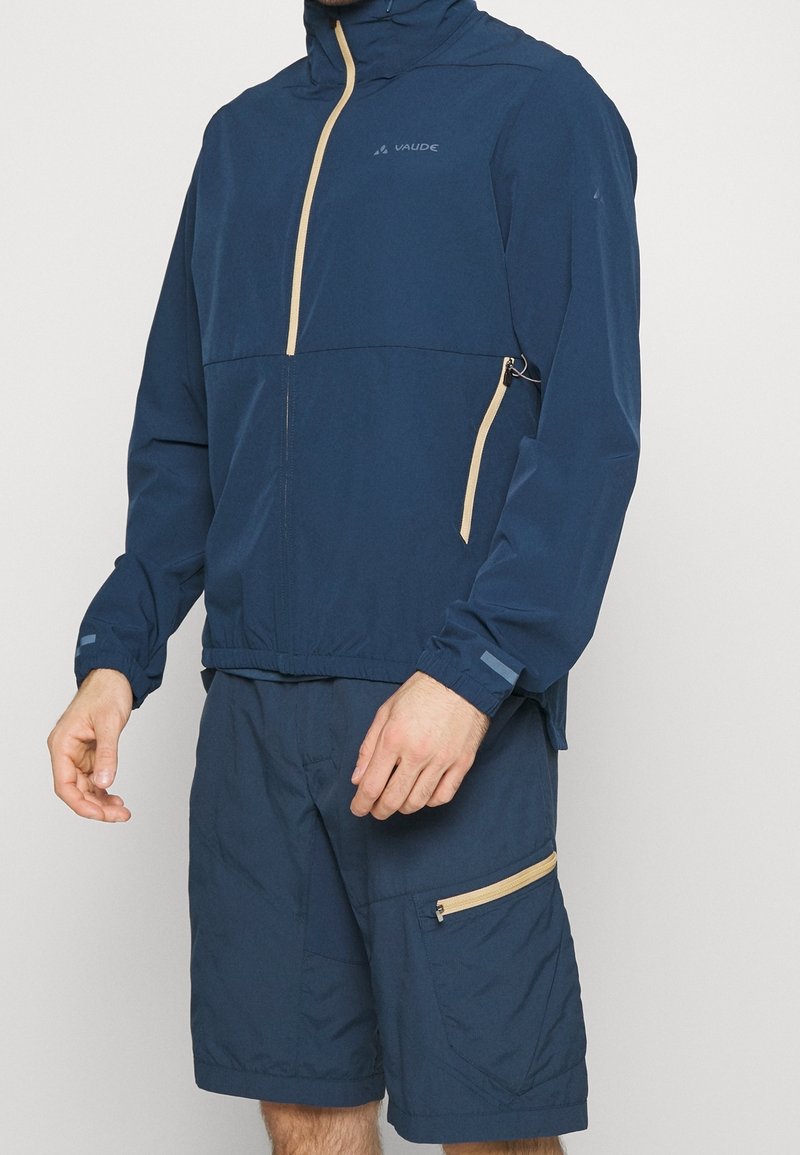 Marinblå lättviktsjacka med dragkedja fram och beige detaljer, matchad med koordinerande shorts med sidofickdragkedja.