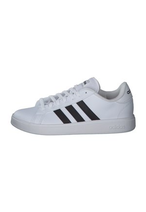 Zapatilla blanca de Adidas con tres franjas negras, cierre de cordones, cuello acolchado y suela y lengüeta de talón con la marca.