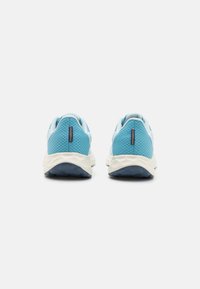 Zapatillas deportivas de color azul claro con parte superior de malla texturizada, mediasuelas blancas y suelas exteriores de goma azul, con un detalle de la marca en el talón.
