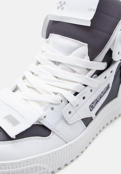 Λευκό και μαύρο ψηλό αθλητικό παπούτσι Off-White με λευκά κορδόνια, δέρμα με υφή και λεπτομέρεια με γραμμωτό κώδικα στο λουρί της γλώσσας.