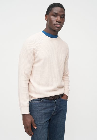 Svetloružový rebrovaný sveter s dlhými rukávmi, dizajnom s okrúhlym výstrihom, v kombinácii s tmavomodrými džínsami a hnedým opaskom. Hladká textúra a priliehavý strih.