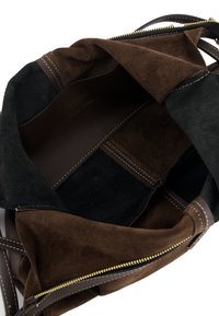 Brown suede tote bag with a zippered opening, black suede accents, and dark leather straps. Interior features a smooth lining and multiple compartments.