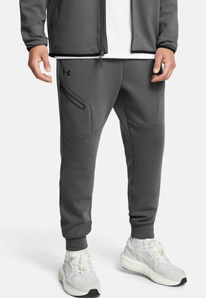 Gray sweatpants made of soft material, featuring a zippered pocket and tapered ankles. Worn with white sneakers for added contrast.
