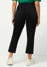 Pantalones de mezclilla negros con una cintura elástica, de longitud corta y una textura suave, combinados con zapatillas de plataforma blancas.