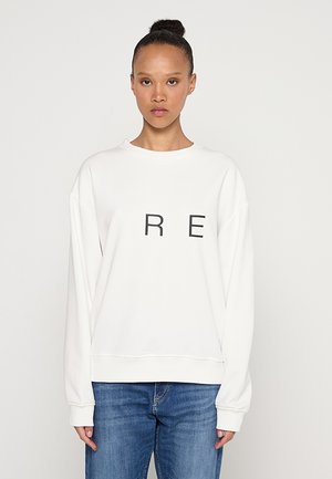 Sweat-shirt blanc à manches longues, col rond, avec de grandes lettres noires 'R E' imprimées sur le devant. Tissu doux, coupe décontractée, design casual.