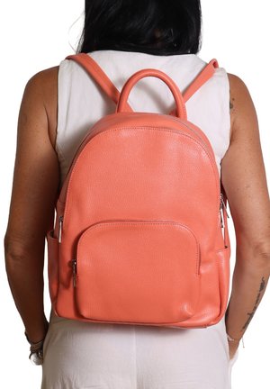 Sac à dos en cuir corail au design arrondi, doté de sangles ajustables, d'une poignée supérieure et d'une poche zippée à l'avant. Surface texturée.