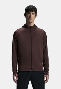 Felpa con zip marrone realizzata in tessuto leggero. Presenta un colletto alto, maniche lunghe e un logo del marchio sul petto. Design semplice.