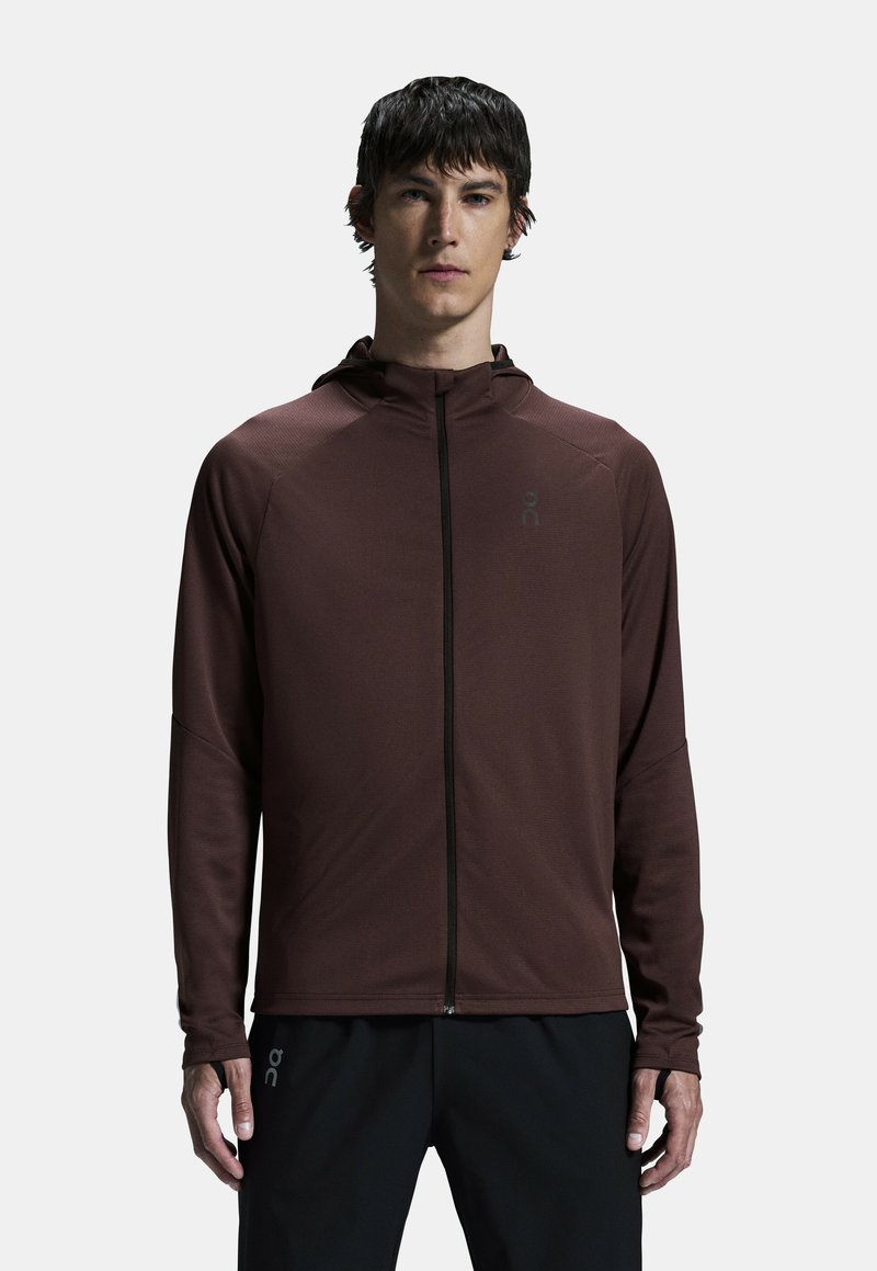 Felpa con zip marrone realizzata in tessuto leggero. Presenta un colletto alto, maniche lunghe e un logo del marchio sul petto. Design semplice.