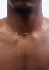 Silberkette, die auf einer glatten Haut liegt, mit einem zarten, filigranen Design und einem dezenten Glanz.