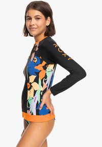 Longsleeve rash guard z czarnym tłem, kolorowymi wzorami kwiatowymi, pomarańczowymi akcentami i zamek z przodu dla łatwego zakupu.
