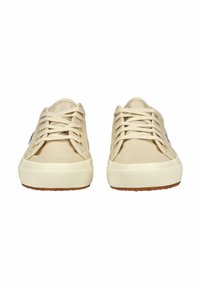 Zapatillas de lona beige con punta redonda, diseño plano con cordones, suela de goma texturizada y detalles minimalistas.