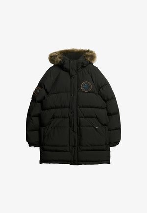 Zwarte pufferjas met een bont-gevoerde capuchon, grote gequiltte stukken, twee voorzakken en een ronde patch op de borst.