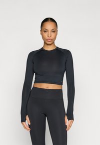 Black cropped long-sleeve top made of stretchy fabric with a round neckline and fitted design, paired with high-waisted black leggings.