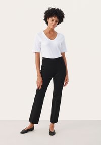Witte kortebloesem V-hals t-shirt gecombineerd met hoge zwarte broeken. Zwarte flats met een puntige neus maken de outfit compleet.