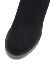 Melnas zamšādas potītes zābaki ar noapaļotu purngalu, minimālistisku dizainu un biezu melnu gumijas zoli. Gluda tekstūra bez redzamām akcentēm.