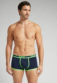 Marinblå kalsonger med ljusgröna detaljer, med en elastisk midjeband med varumärke och en tajt passform. Slätt tyg med en enkel design.