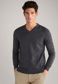 Dunkelgrauer V-Ausschnitt-Pullover mit langen Ärmeln, aus einem glatten Strickmaterial gefertigt und mit gerippten Bündchen und Saum. Minimales Logo-Detail am unteren Rand.