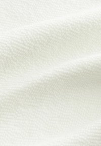 Tissu blanc texturé avec un motif tissé, présentant de subtiles ondulations et une apparence douce et légère. Idéal pour diverses applications.