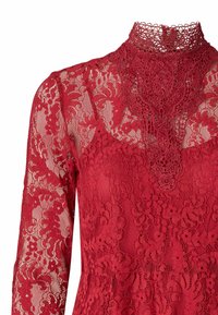 Červené čipkované šaty s vysokým golierom, dlhými rukávmi, zložitými kvetinovými vzormi a textúrovaným povrchom. Čipkový prehoz pridáva dizajnu detaily.