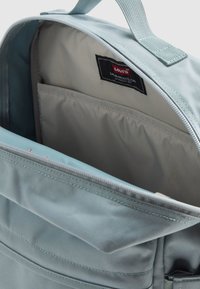 Το εσωτερικό του ανοιχτό μπλε σακιδίου διαθέτει λείο, ανοιχτόγριζο επένδυση, μια τσέπη και μια μαύρη ετικέτα Levi's ραμμένη στο πλάι.