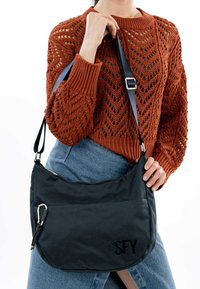 Borsa a spalla in rete nera con una texture liscia, tracolla regolabile e dettagli in argento. Presenta il logo SFY in un font moderno.