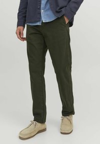 Olive green pants made of soft cotton, featuring a straight leg design, side pockets, and a smooth texture. Worn with light footwear.