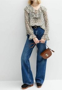 Blouse fleurie avec manches volantées, associée à un jean large en denim bleu taille haute. Sac bandoulière marron et sabots noirs à clous.