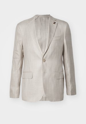 Blazer en lin beige clair avec un revers cranté, fermeture à bouton unique, deux poches avant et une texture tissée subtile. Comprend une épingle décorative.