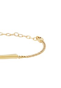 Pulsera de oro con dos estilos de cadena: una sección de barra lisa y una cadena enlazada con un cierre cuadrado sobre un fondo blanco.