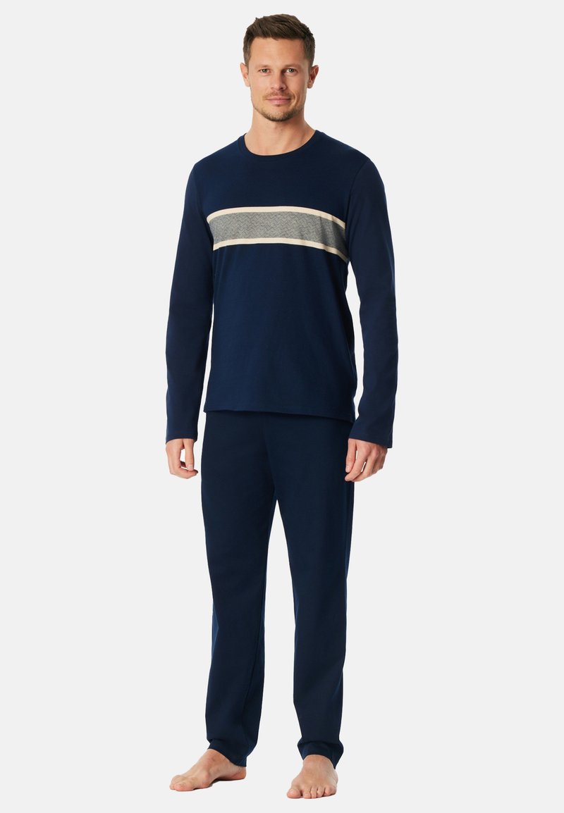 Ensemble de vêtements d'intérieur bleu marine composé d'un haut à manches longues avec un motif à rayures gris clair et crème, et d'un pantalon assorti. Texture de tissu douce.