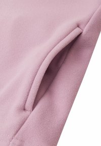 Tessuto rosa chiaro con una morbida texture, dotato di un dettaglio con tasca laterale, bordi cuciti e una finitura liscia, adatto per abbigliamento casual.