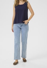 Marinblå ärmlös topp med rund halsringning, parat med ljusblå raka jeans och bruna slip-on skor. En enkel och avslappnad outfit.