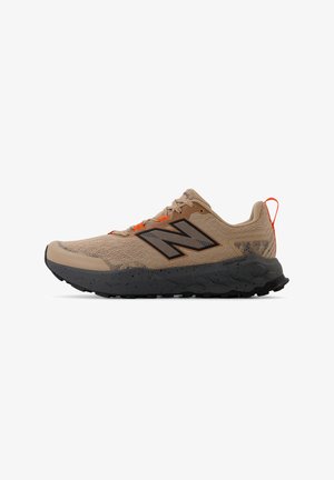 Beige athletic shoe with black detailing, mesh upper, speckled midsole, and bright orange laces. Grooved black outsole for traction.