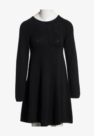 Vestido negro de punto con mangas largas, escote redondo y falda acampanada, mostrado en un maniquí.
