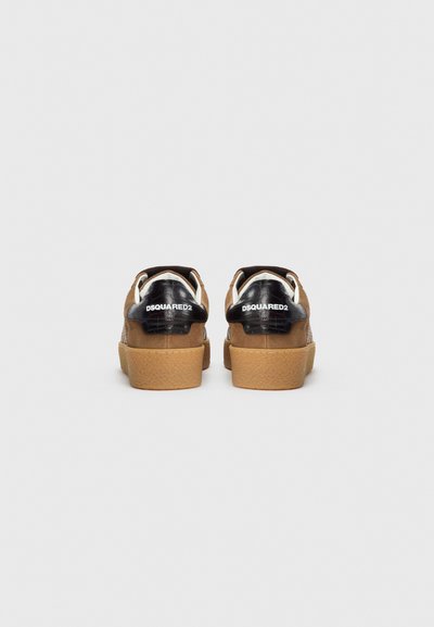 Brown suede sneakers with black textured heel, logo on rear, gum sole, and white accents. Classic design with distinctive cushioning.
