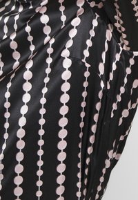 Tela de satén negra con un diseño de patrones circulares rosa alternos y líneas verticales, creando una apariencia texturada y en capas.