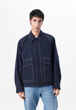 Navy blue outer jacket with a collar, visible stitching, and two front pockets. Made from a smooth, durable fabric with a relaxed fit.